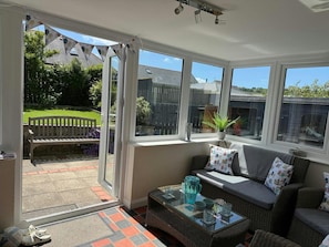 Conservatory with table and chairs and double doors leading to the garden