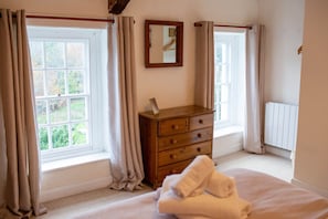 Two windows overlooking garden. Chest of drawers with mirror over