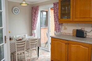 kitchen cabinets, dining table to seat for dressed for dinner, patio doors leading to decking area