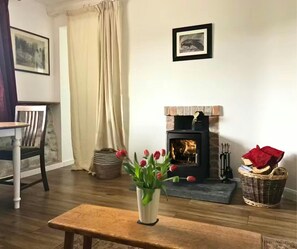 Fireplace, logs and safety gloves, a bin for ash, companion set, coffee table with tulips in a vase
