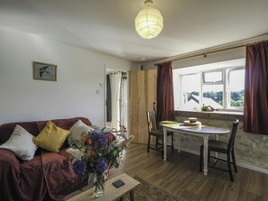 Table and 2 chairs, sofa, cushions and flowers in a vase on the coffee table
