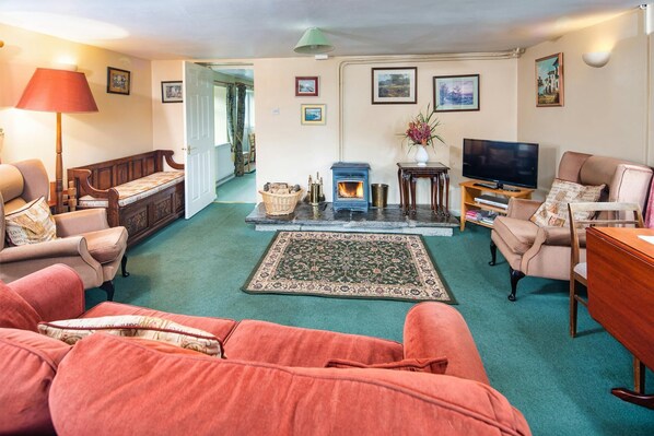 Red fabric sofa, two arm chairs TV and wood burning stove