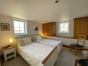 Twin beds, bedside tables, lamps, chair and 2 windows