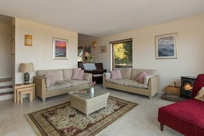 Two sofas and coffee table. Piano and woodburner