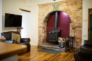 Stone fire place with wood burner inside. Wall mounted TV