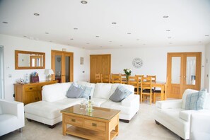 Corner sofa, armchairs, coffee table and dining table and chairs in the background