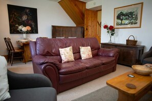 Living room with sofa, armchair, dining area with small table and 4 chairs