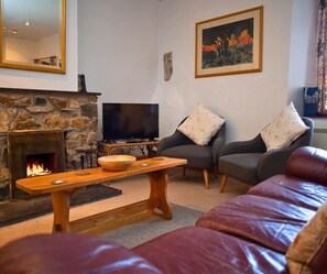 Lounge with sofa, armchairs, open fire, bench used as a coffee table, tv