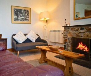 Living room with large sofa and small sofa, bench used as coffee table, open fire