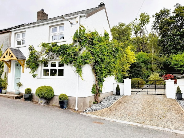 Outside of the cottage with mature wisteria and driveway with parking
