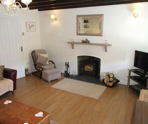 Lounge with woodburner, tv, sofa and armchair
