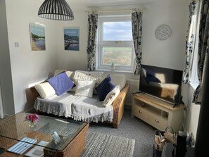 TV, coffee table and two seater sofa. Double aspect windows with views