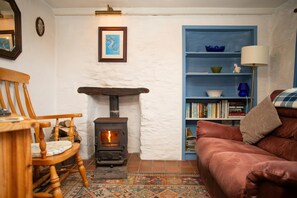 Sitting area with sofa, woodburner, armchair, bookshelf