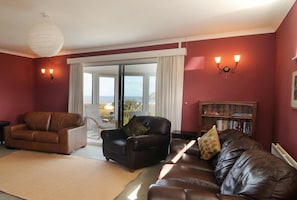 Living room with sofa, armchair, doors leading to conservatory