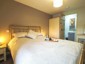 King size bed with brass head and foot frame. Wardrobe, bedside table and lamps
