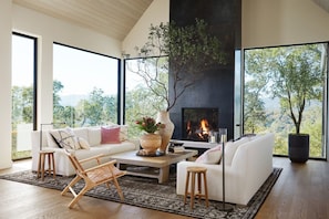Cozy up next to the fireplace in this stunning living room with expansive views and luxury furniture.