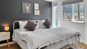 A spacious bedroom with a plush king-sized bed offers an inviting space to recharge and enjoy the stunning views over the lake.