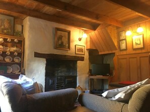 Living room with arm chairs, TV Fireplace, welsh dresser with cookware set.