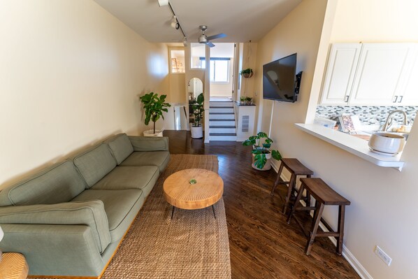 Living room, featuring a 3 seater couch, smart TV. decorated with live plants.