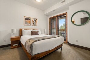 Primary bedroom with a queen bed, access to the patio, walk-through closet & private ensuite bathroom
