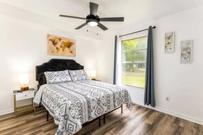 The bedroom 1, is bright and cozy, with plenty of natural light, tasteful decorations, a ceiling fan, a double bed, nightstands with lamps, and a wardrobe.