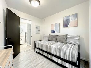 The room has a cozy sofa bed with a pull-out trundle bed, it also includes a chest of drawers with ample drawers.