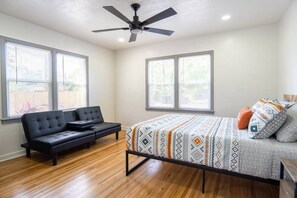Room with a queen bed, sofa, and ceiling fan.