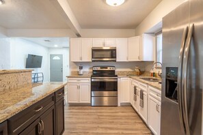 Kitchen with a 4-burner stove, microwave, large refrigerator, and plenty of cabinets for storage.