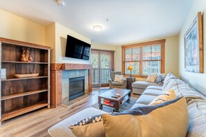 Living area featuring mounted flat screen TV, hardwood flooring, gas fireplace, cozy furniture and access to the private balcony