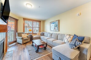 Living area featuring mounted flat screen TV, hardwood flooring, gas fireplace, cozy furniture and access to the private balcony