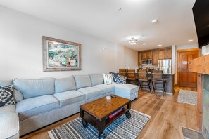 Living area featuring mounted flat screen TV, hardwood flooring, gas fireplace, cozy furniture and access to the private balcony