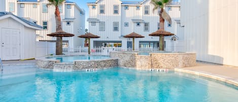 Outdoors - Inviting community pool with clear blue water, surrounded by comfy loungers and straw covered structures