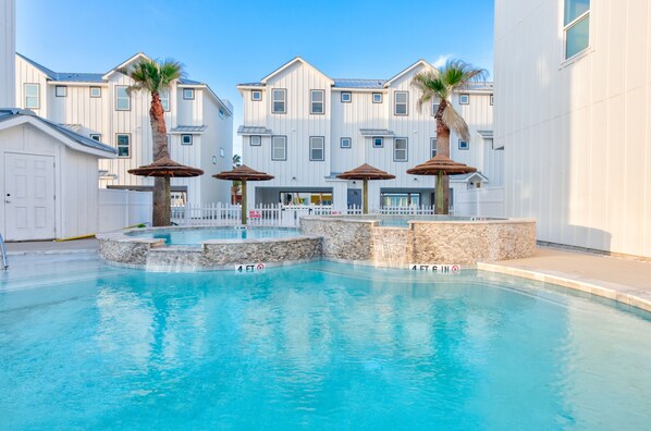Outdoors - Inviting community pool with clear blue water, surrounded by comfy loungers and straw covered structures