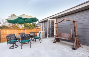 Unwind in the spacious backyard featuring a rustic bench swing, an iron dining set for six, and a solar-lit umbrella that tilts for perfect shade any time of day. With direct access to the kitchen and a secure mesh screen door, this outdoor space is ideal