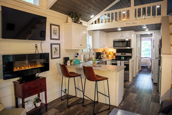 Cozy farmhouse style tiny house with electric fireplace and wifi for streaming or working from home in a new scenery. Fully functioning and stocked kitchen. Master bedroom is on the main floor along with bunkbeds. 