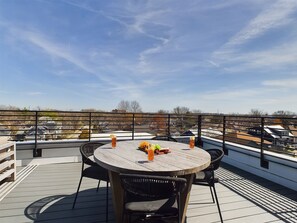 Unit 5: Private 4th-story balcony featuring outdoor furnishings for lounging and dining offering neighborhood and city views.