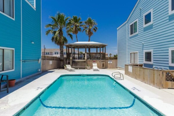 Enjoy a refreshing swim in the sparkling pool surrounded by lush greenery and cozy lounge chairs. Perfect for soaking up the sun or cooling off, this inviting area offers the ideal place to relax and recharge.