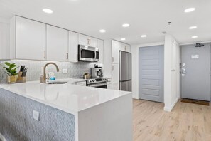 Beautifully remodeled kitchen with stainless steel full sized appliances, cookware, dishwater, bakeware, regular and Keurig coffee makers, large quartz peninsula with waterfall edge and convenient pantry cabinet.  