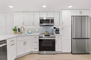 Beautifully remodeled kitchen with stainless steel full sized appliances, cookware, dishwater, bakeware, regular and Keurig coffee makers, large quartz peninsula with waterfall edge and convenient pantry cabinet.  