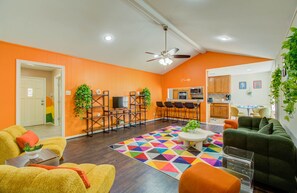 Main living room with large plush couch, TV rack, and bar seating for 4