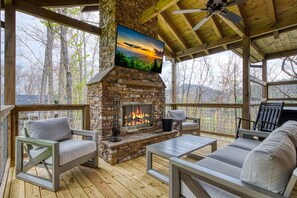 Covered deck with 65" 4K Smart TV, cushioned seating, and hot tub