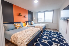 Chic and cozy queen beds with vibrant decor and city views