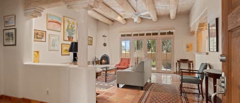 Unwind in the inviting living area, which features a cozy kiva fireplace, tall ceilings with white-washed lodge-pole beams, and large glass French doors leading to the private courtyard.