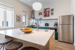 Sleek kitchen features an island with barstool seating.