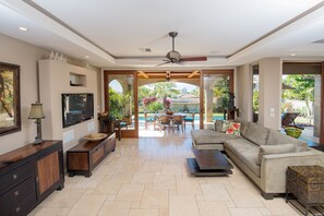 Enjoy the view of the outdoor pool and lush garden from this stylish living room with seamless indoor-outdoor living design."
