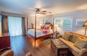 Unwind in this master bedroom, featuring a four-poster bed, cozy sitting area, and direct access to the patio.