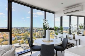 Enjoy meals in the open-plan dining area, where a charming wooden round table and upholstered chairs sit beneath the comfort of air-conditioning and uninterrupted city views. 

