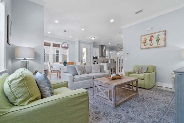A spacious and beautifully decorated living area with soft pastel tones, modern furniture, and an open-concept design.