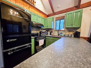 Green with envy! This kitchen features stunning green cabinets and sleek black appliances.