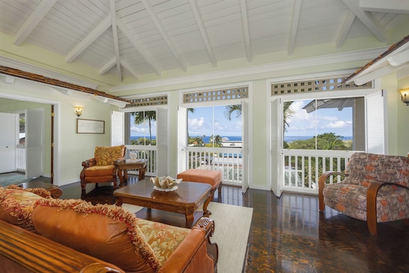 Spacious living area with ocean views, cozy furniture, and high ceilings.